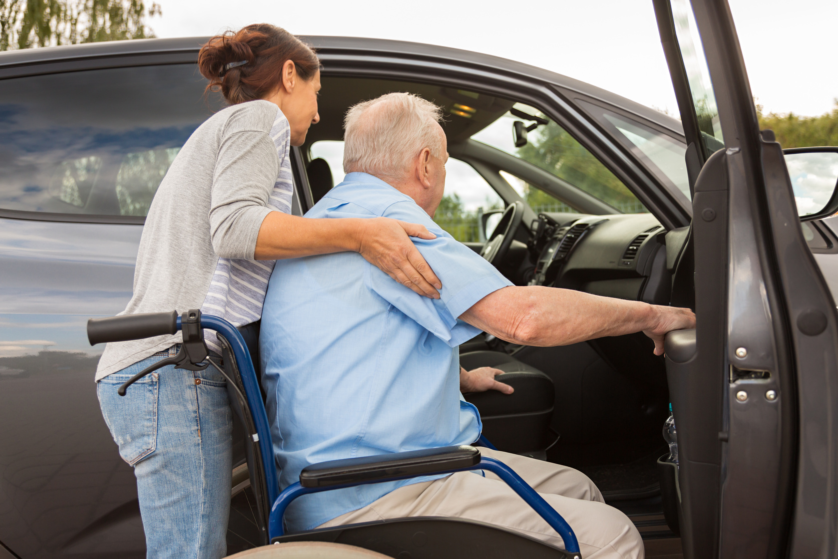 Caregiver helping senior into car